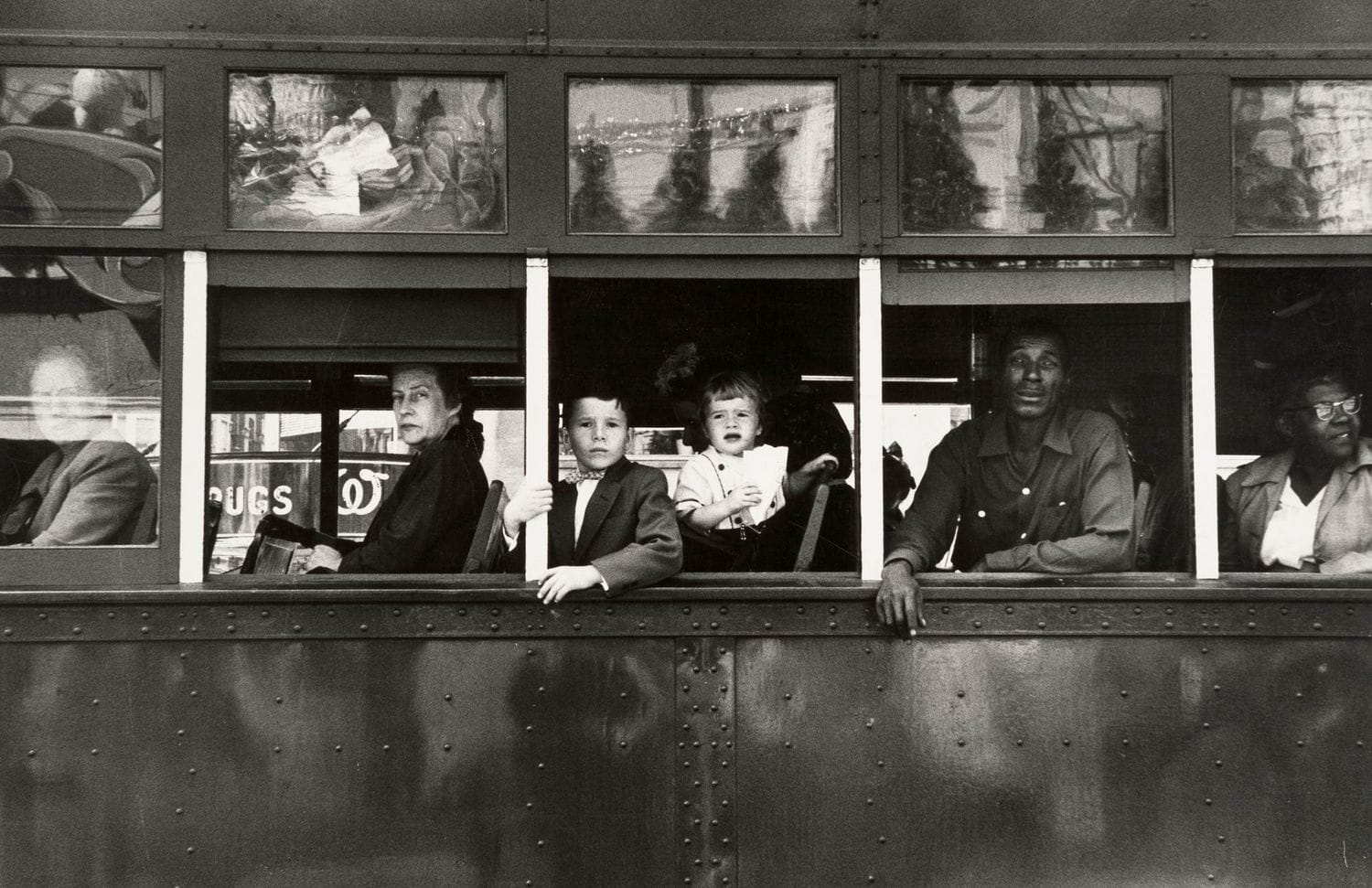 A side view of a trolly. White people are in the front, black people in back. The class differences are stark.