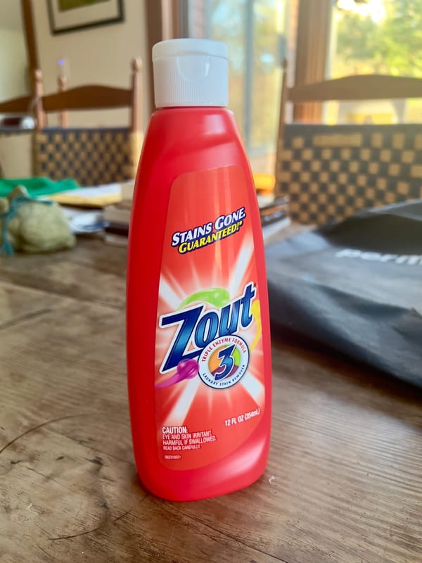 A bottle of Zout stain remover sits on a table